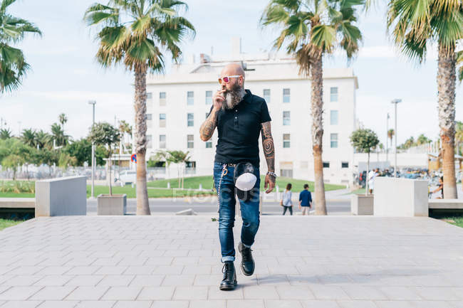 Hombre maduro hipster fumando cigarrillo y paseando por la ciudad, Valencia, España - foto de stock