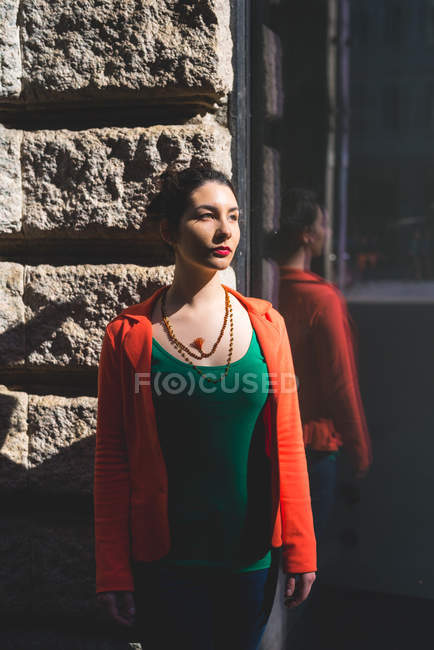 Mujer joven de pie junto a la pared, Milán, Italia - foto de stock