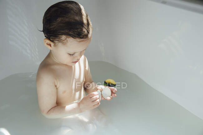 Девушка в ванной играет с ванной игрушкой — стоковое фото