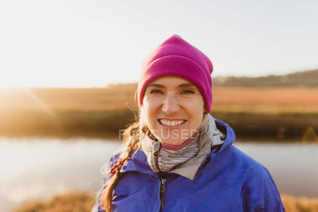 Porträt einer Frau mit rosa Hut am Ufer des Flusses bei Sonnenuntergang, Morro Bay, Kalifornien, USA — Stockfoto