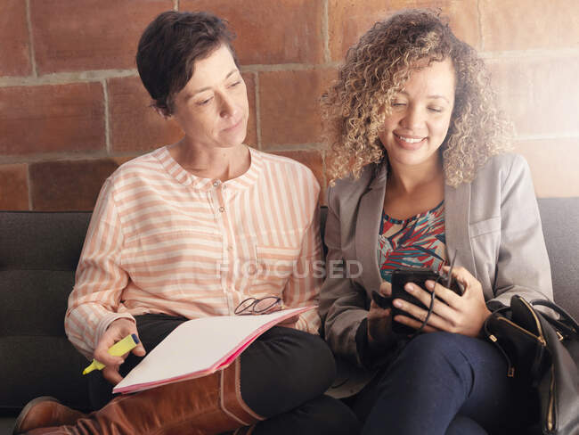 Colleagues with paperwork and cellphone — Stock Photo