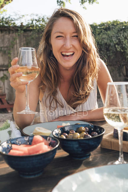Portrait of young woman sitting at table with wine glass — Stock Photo