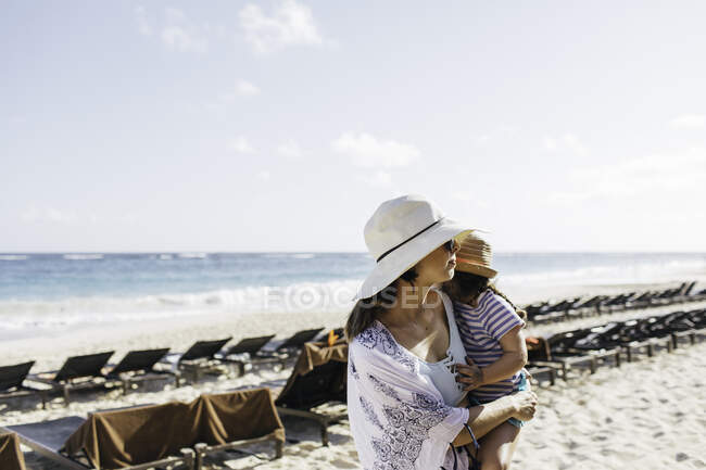 Мати ходить на пляжі, носить молоду доньку — стокове фото