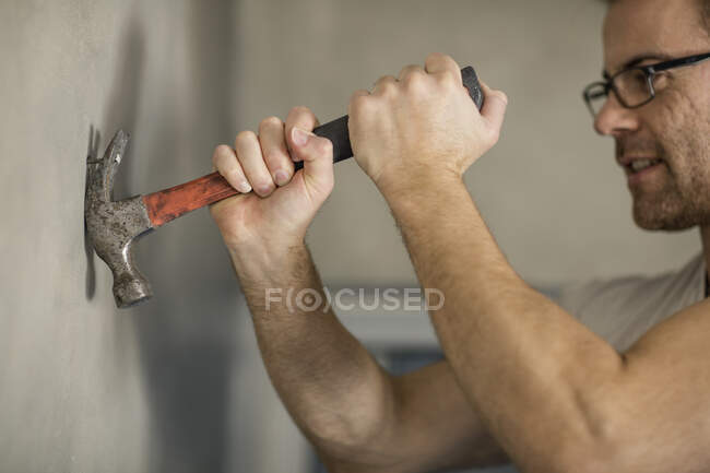 Человек берет гвоздь из стены, используя молоток — стоковое фото