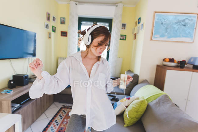 Молода жінка в навушниках танцює у вітальні — стокове фото
