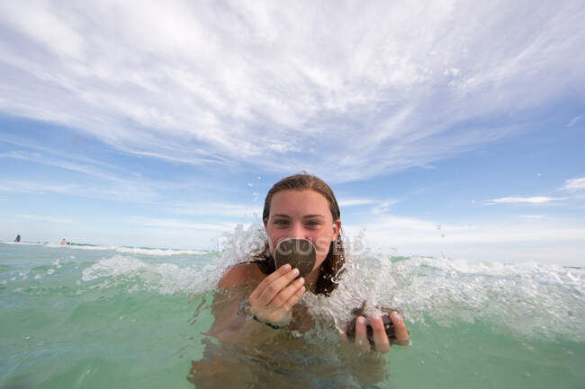 Portrait of young woman in water, holding shells — Stock Photo