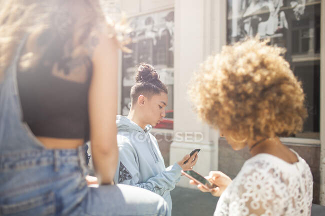 Três jovens amigos ao ar livre, olhando para smartphones — Fotografia de Stock