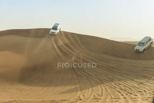 Vehículos todoterreno conduciendo por dunas del desierto, Dubai, Emiratos Árabes Unidos - foto de stock