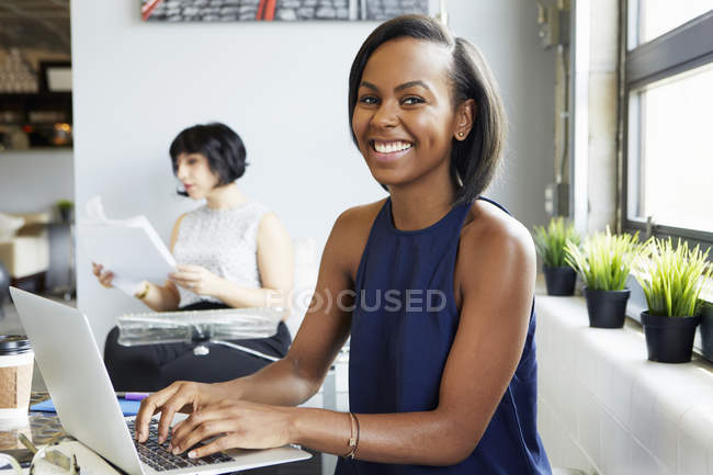Portrait of woman working on laptop in modern office — Stock Photo