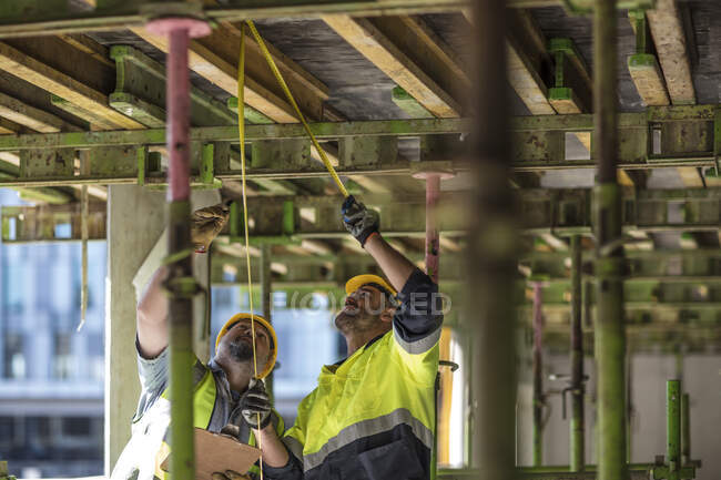 Travailleurs de la construction mesurant bâtiment — Photo de stock