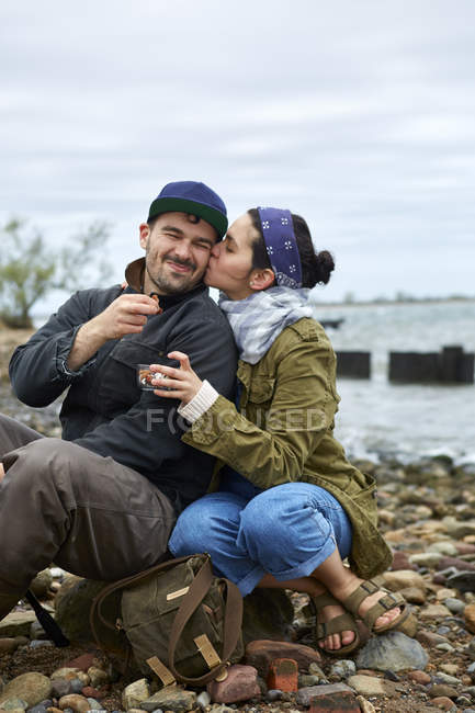 Giovane donna baciare fidanzato sulla guancia sulla spiaggia — Foto stock