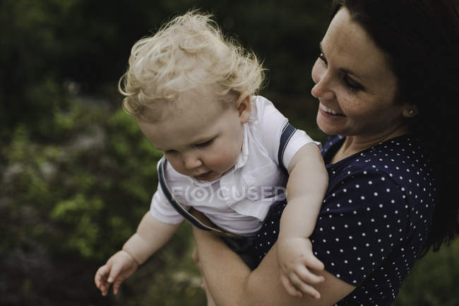 Середня доросла жінка, що носить маленького сина на руках — стокове фото