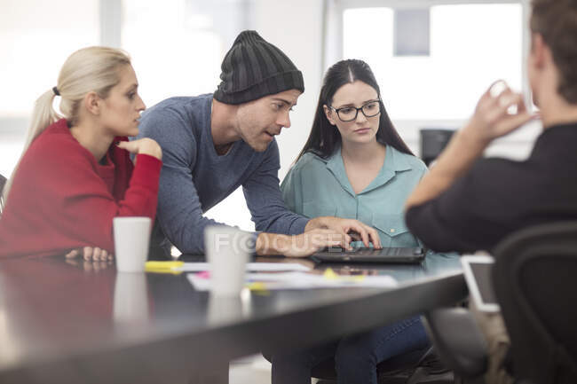 Male and female office workers typing on laptop at meeting — Stock Photo