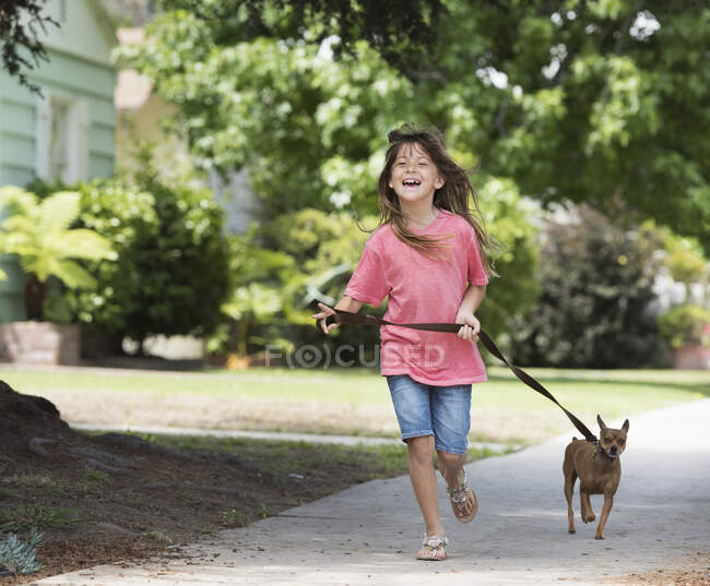 Girl walking dog in street — Stock Photo