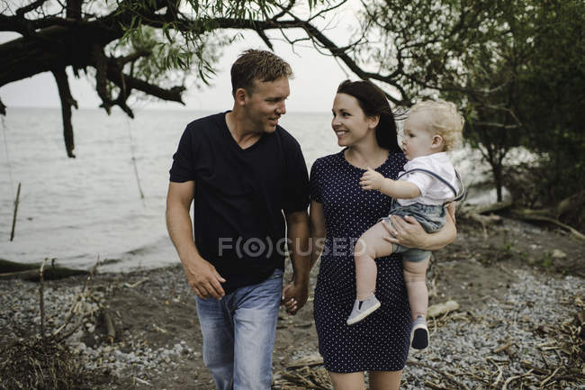 Pregnant couple hand in hand on beach with male toddler son, Lake Ontario, Canada — Stock Photo