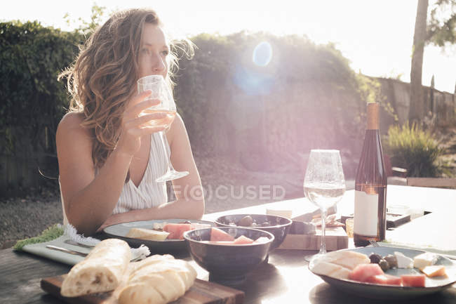 Portrait de jeune femme assise à table avec verre à vin — Photo de stock