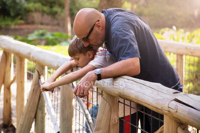 Father and son standing on footbridge, looking over edge at water below — Stock Photo