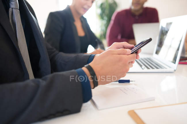 Cropped shot of businessman looking at smartphone during meeting — Stock Photo