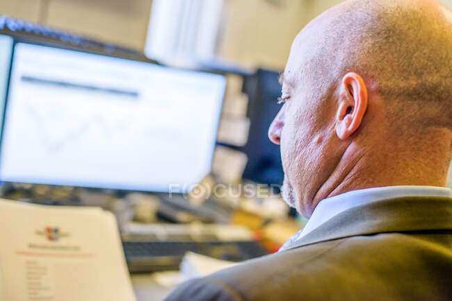 Over shoulder view of businessman reading paperwork at office desk — Stock Photo