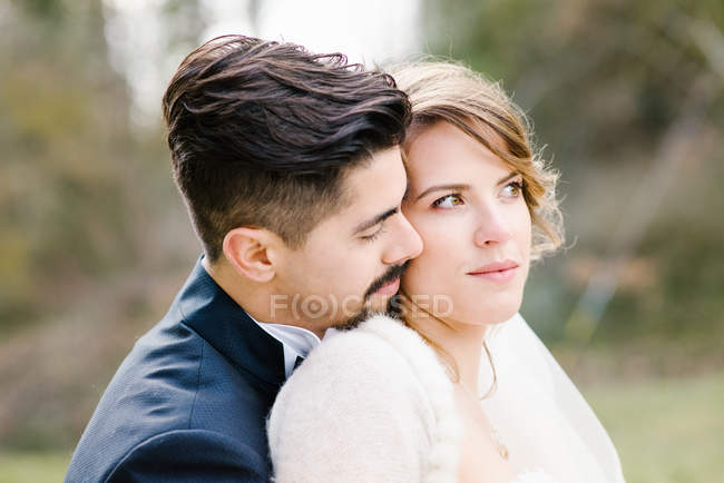 Retrato de novia y novio abrazándose al aire libre - foto de stock
