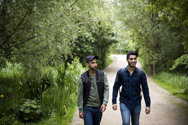 Two friends walking on pathway in park — Stock Photo