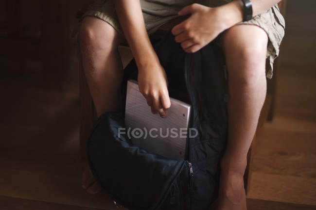 Cropped image of boy packing backpack and putting notebook — Stock Photo