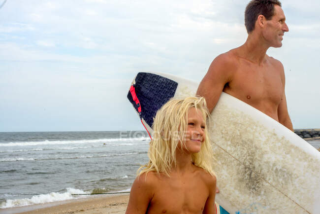 Mature male surfer on beach with blond haired son, Asbury Park, New Jersey, USA — Stock Photo