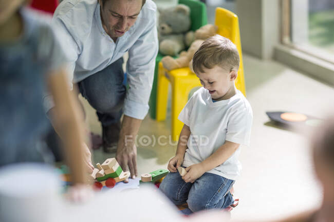 Professeur et garçon jouant avec le train jouet — Photo de stock