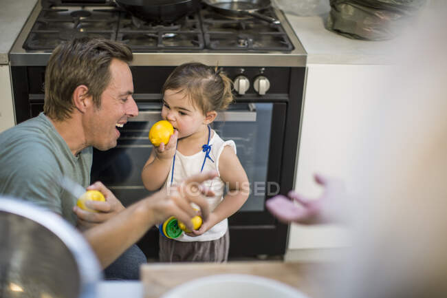 Отец смеется над девочкой, пробуя лимон. — стоковое фото