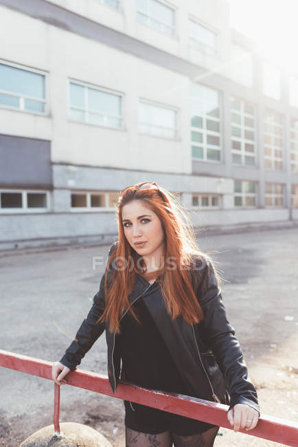 Portrait of red haired woman leaning against railing — Stock Photo