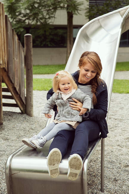 Mãe e filha criança no diapositivo do playground — Fotografia de Stock