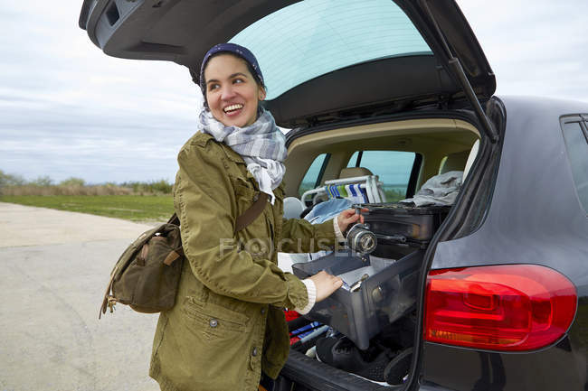 Молода жінка знімає речі з багажника автомобіля — стокове фото