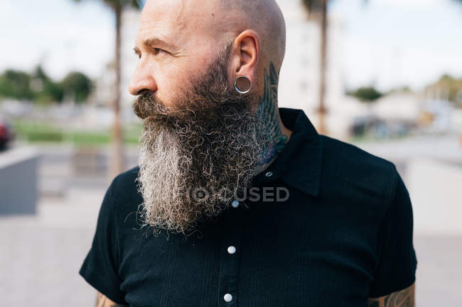 Retrato de hipster macho maduro con barba gris y pendiente plug, cabeza y hombros - foto de stock
