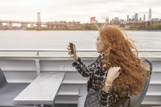 Young businesswoman on passenger ferry deck taking smartphone selfie — Stock Photo