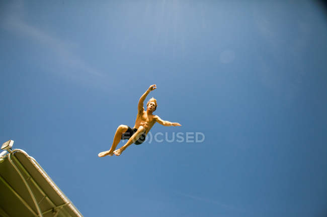Низкий угол зрения молодого человека, прыгающего — стоковое фото