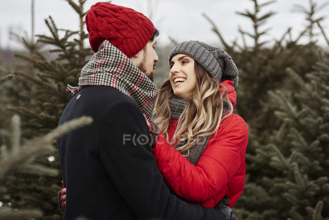 Romántica pareja joven de compras para el árbol de Navidad del bosque - foto de stock