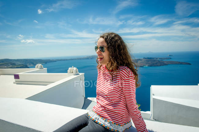 Дівчина розслабляючий на стіну з моря на тлі, Санторіні, Kikladhes, Греція — стокове фото