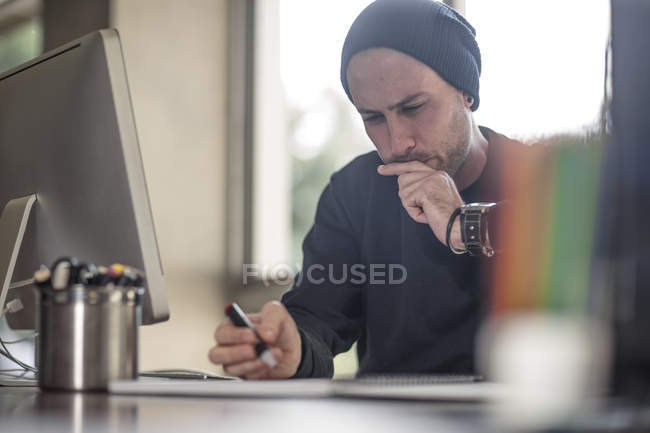 Joven diseñador masculino trabajando en el escritorio del hogar - foto de stock