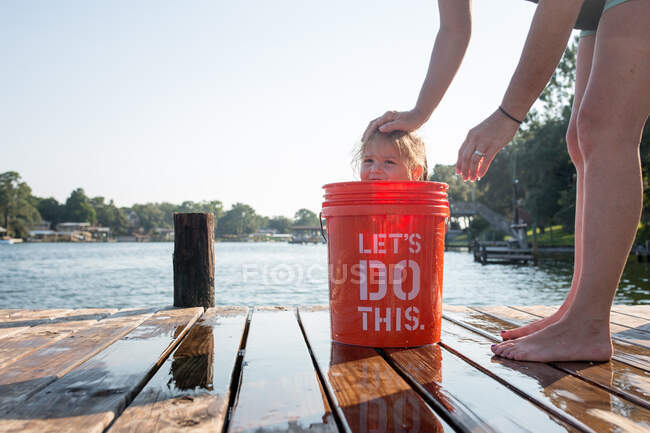 Young girl hiding in bucket on jetty — Stock Photo