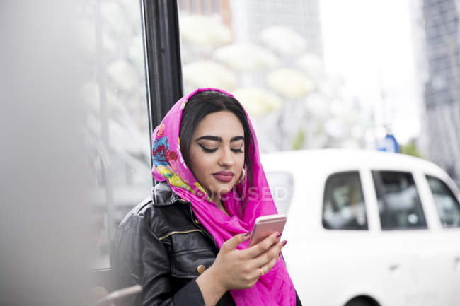 Індійська молодою жінкою використовувати смартфон на автобусній зупинці — стокове фото