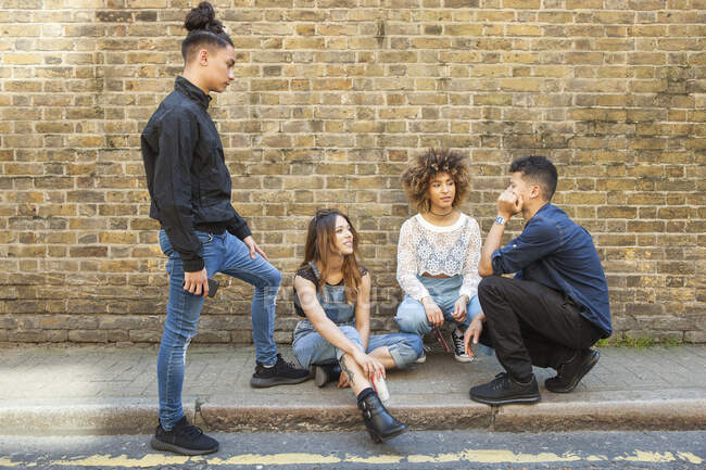 Four friends hanging out in street, talking — Stock Photo