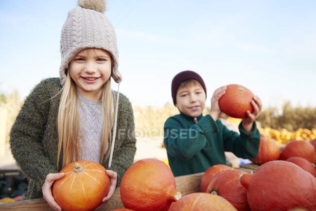 Girl and her brother holding harvested pumpkins — Stock Photo