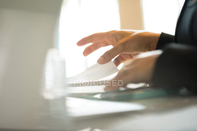 Hands of businesswoman organising paperwork at office desk — Stock Photo