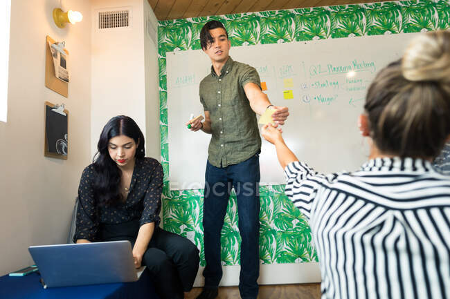 Jovem empresário distribuindo notas adesivas na sala de reuniões criativas — Fotografia de Stock