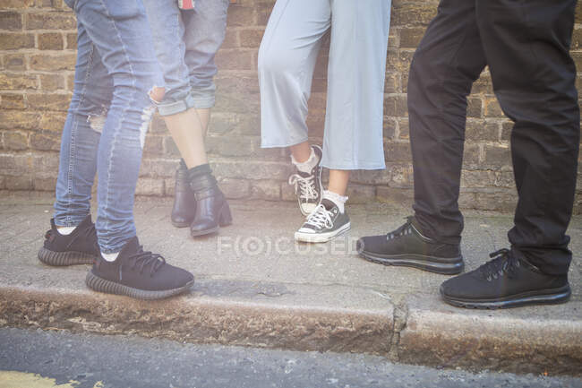 Quatre amis debout dans la rue, section basse — Photo de stock