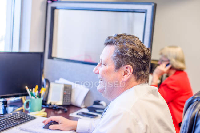 Male office worker using desktop computer at office desk — Stock Photo