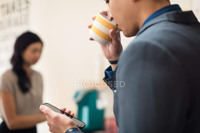 Молодая деловая женщина смотрит на смартфон в офисе — стоковое фото