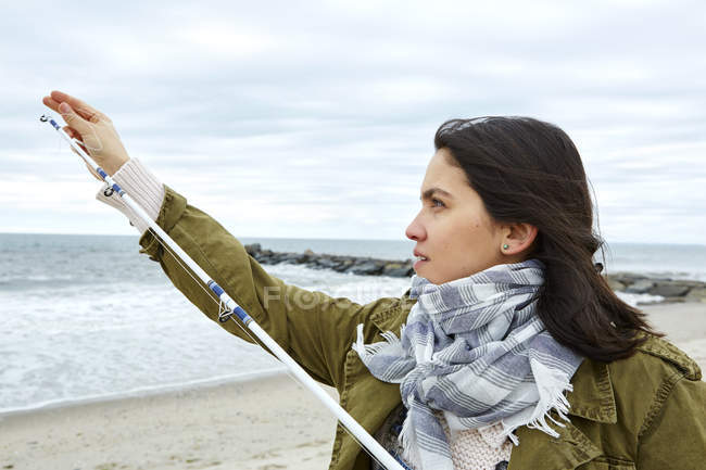 Giovane donna regolazione canna da pesca linea sulla spiaggia — Foto stock