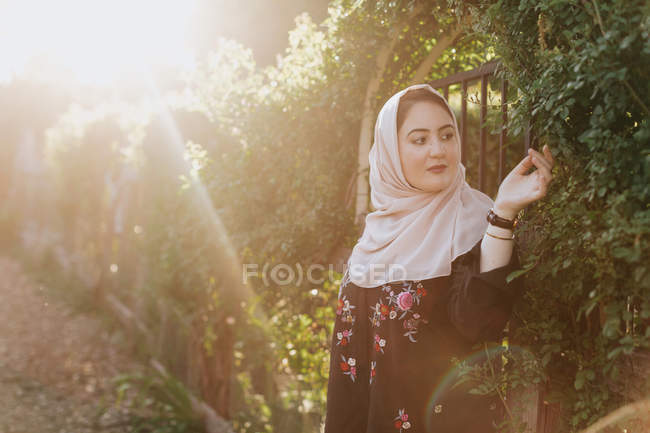 Mujer joven vistiendo en hijab admirando plantas - foto de stock