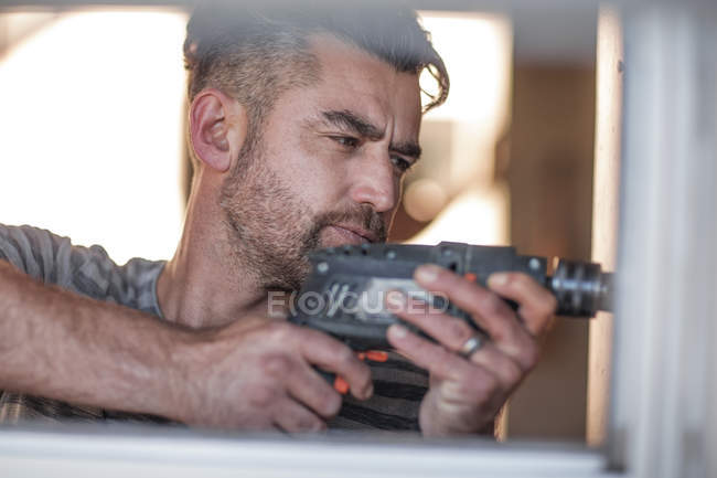 Side view of man drilling into wall — Stock Photo